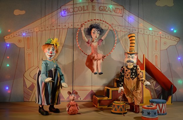 drei Marionetten, ein Clown, eine Trapezkünstlerin, ein Direktor vor Zirkuszelt